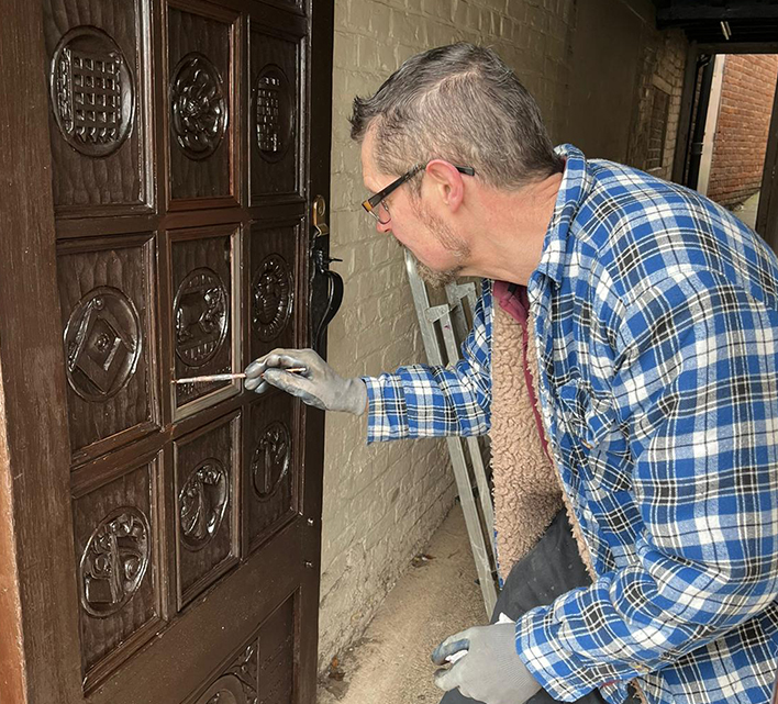 Andrew Brennan adding the final touches to the newly hung and restored door.